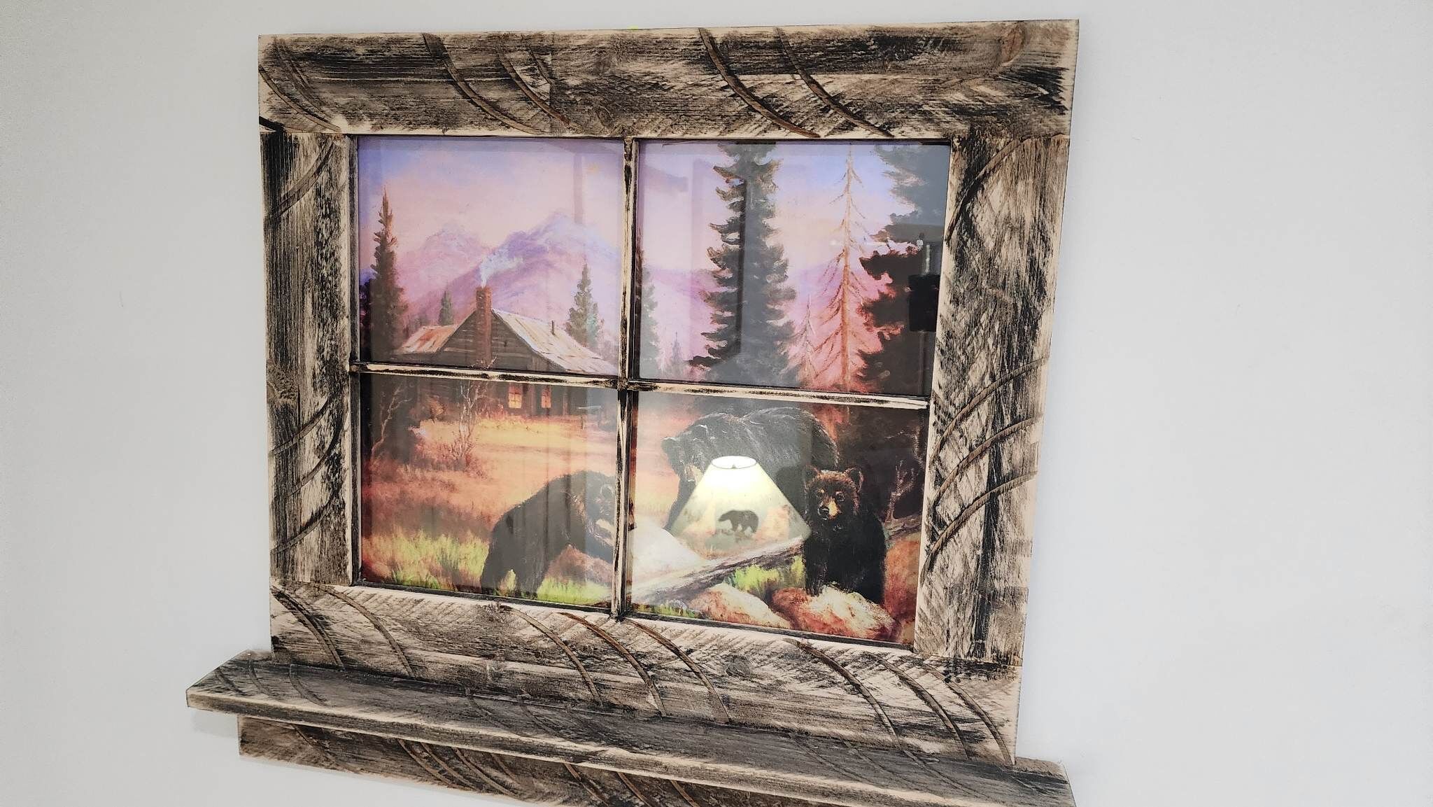 Ein rustikales Holzfenster mit Blick auf eine Hütte im Wald, unterteilt in vier Felder.