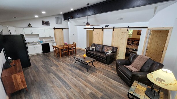 A spacious living area with a dining table and chairs, a sofa, a coffee table, and a lamp. - Jason's Log Cabin Retreat w/ Hot tub, rockers, swing, game room, & 3 King beds (Sevierville)