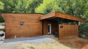 A wooden cabin with a covered porch, a door, and a small window. - Jason's Log Cabin Retreat w/ Hot tub, rockers, swing, game room, & 3 King beds (Sevierville)