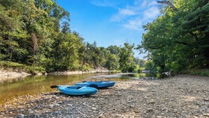Orilla de río con kayaks y costa rocosa.