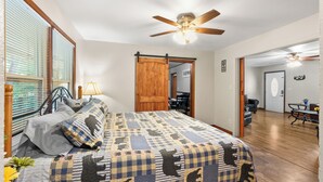 Un dormitorio con una cama grande, un ventilador de techo y vista a un comedor.