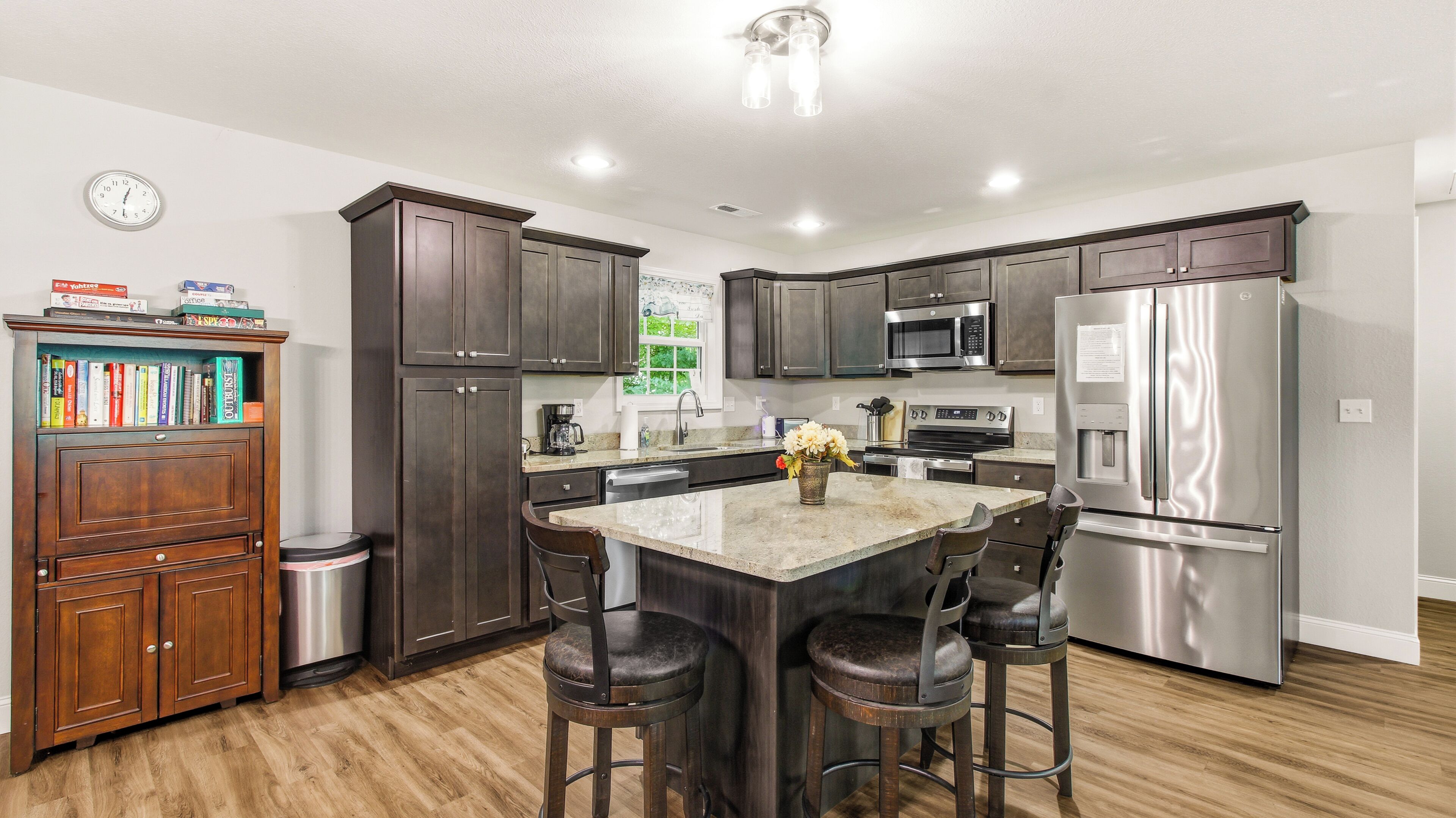 A modern kitchen with dark wood cabinets, stainless steel appliances, and a central island with bar stools.