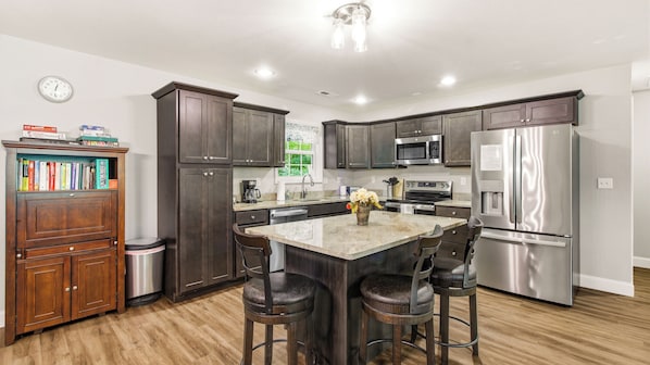 A modern kitchen with dark wood cabinets, stainless steel appliances, and a central island with bar stools.