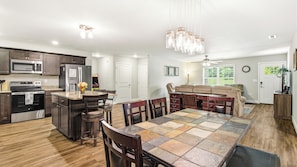 A modern kitchen with stainless steel appliances, a dining area with a large table, and a cozy seating area with a sofa.