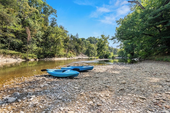 A riverbank with kayaks and a rocky shore.