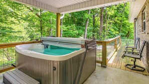 A hot tub on a wooden deck with a view of a forest.