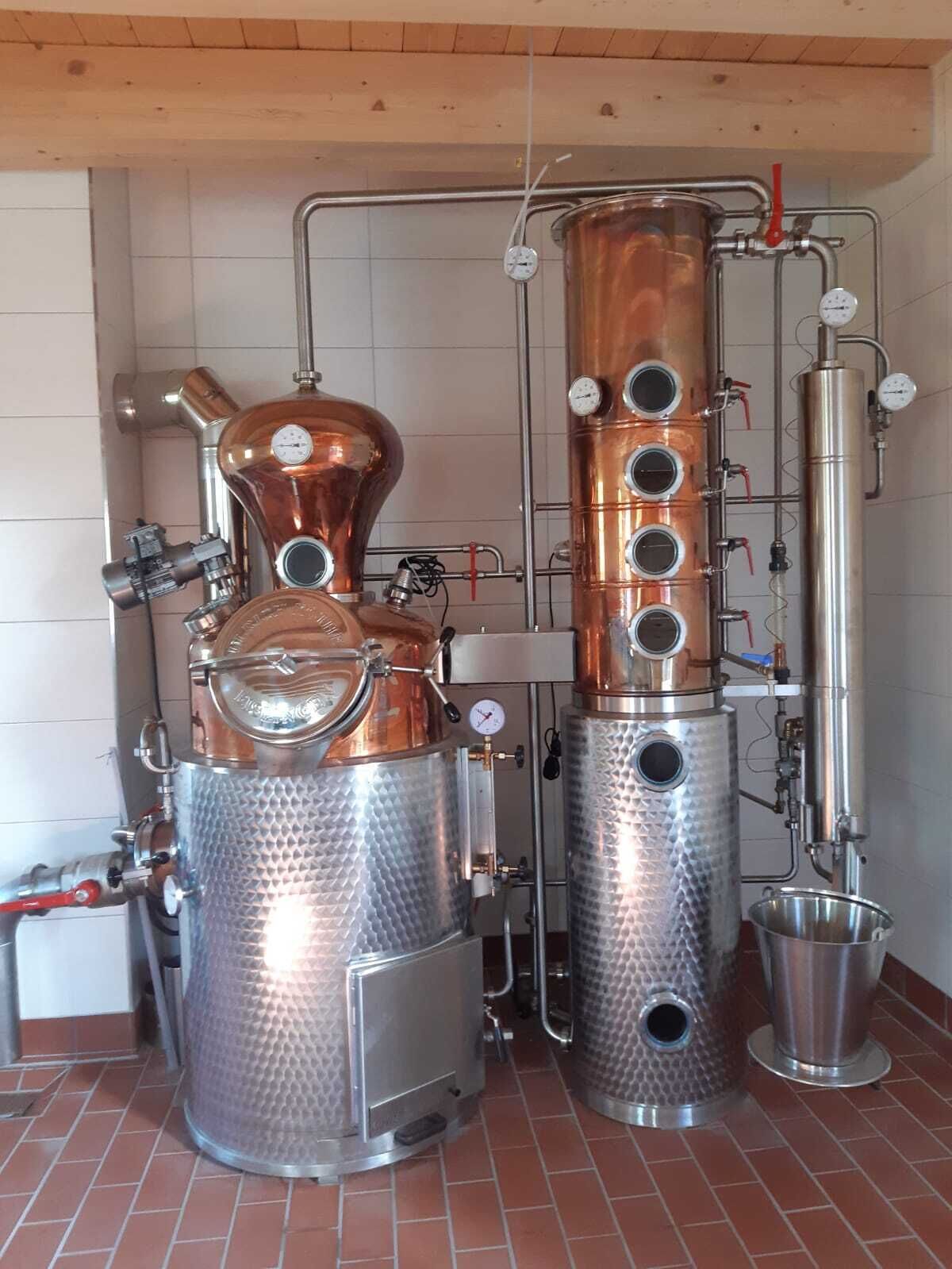 A distillation apparatus with copper and stainless steel components, gauges, and pipes.