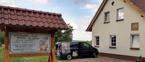 A house with a sign for 'Distillery House Hof Regner' and a van parked in front.