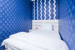 A neatly made bed in a room with blue patterned walls and a white headboard. - Kalimosodo Staycation (Malang)