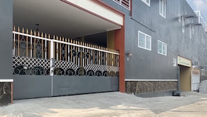 Um edifício de dois andares com entrada fechada por portão, varanda e placa indicando custo exclusivo em Java Malang.