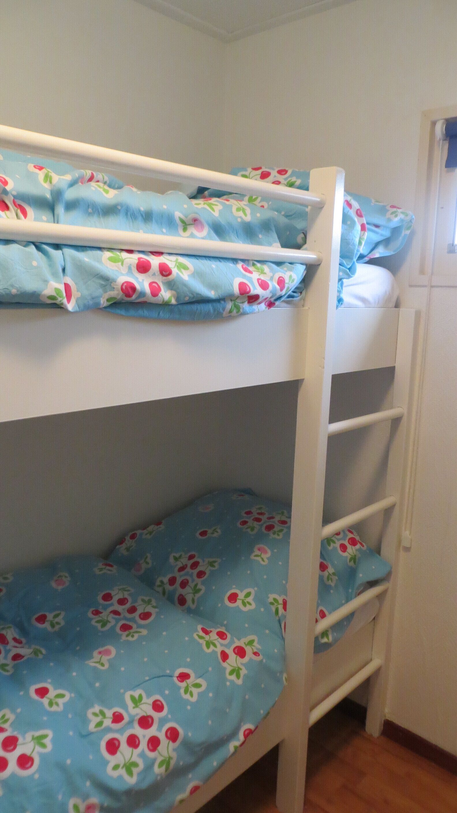 Una cama litera con ropa de cama azul decorada con cerezas.
