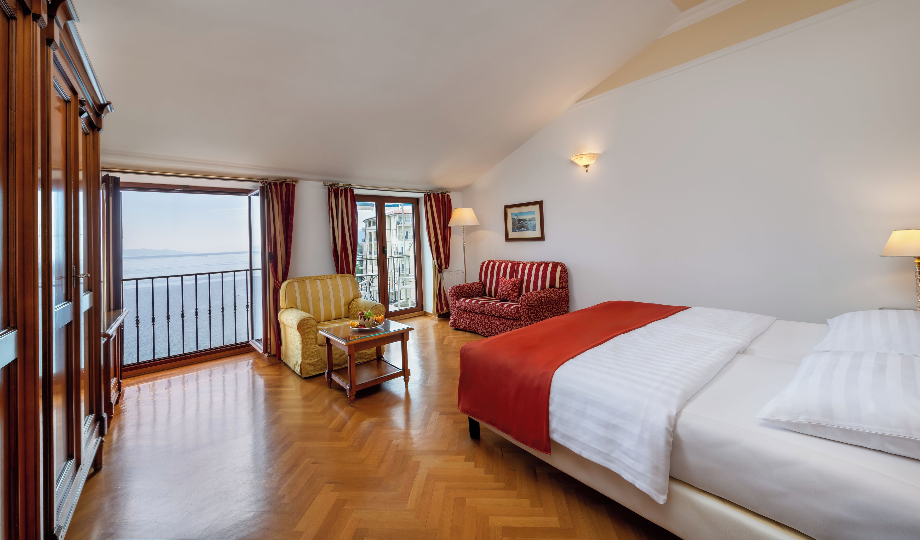 Ein Hotelzimmer mit Bett, einer Couch, einem Sessel, einem Tisch und einem Balkon mit Blick.