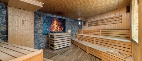 A sauna with wooden benches and a stone wall.