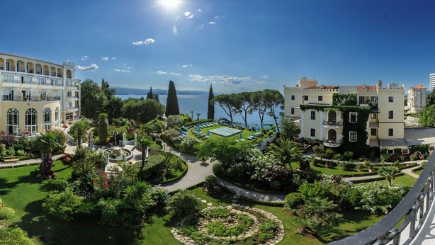 Ein Hotel mit Pool, üppigem Garten und Meerblick.