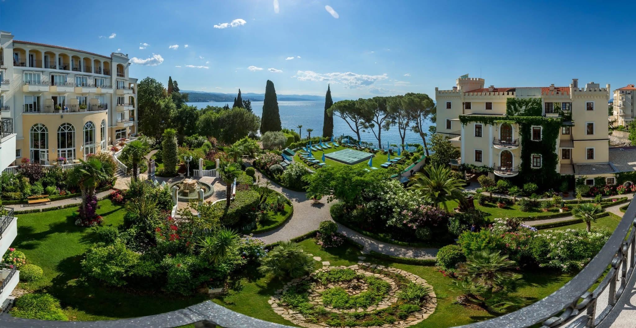 Une cour d’hôtel avec une piscine, entourée d’une végétation luxuriante et dotée d’une architecture de style méditerranéen.