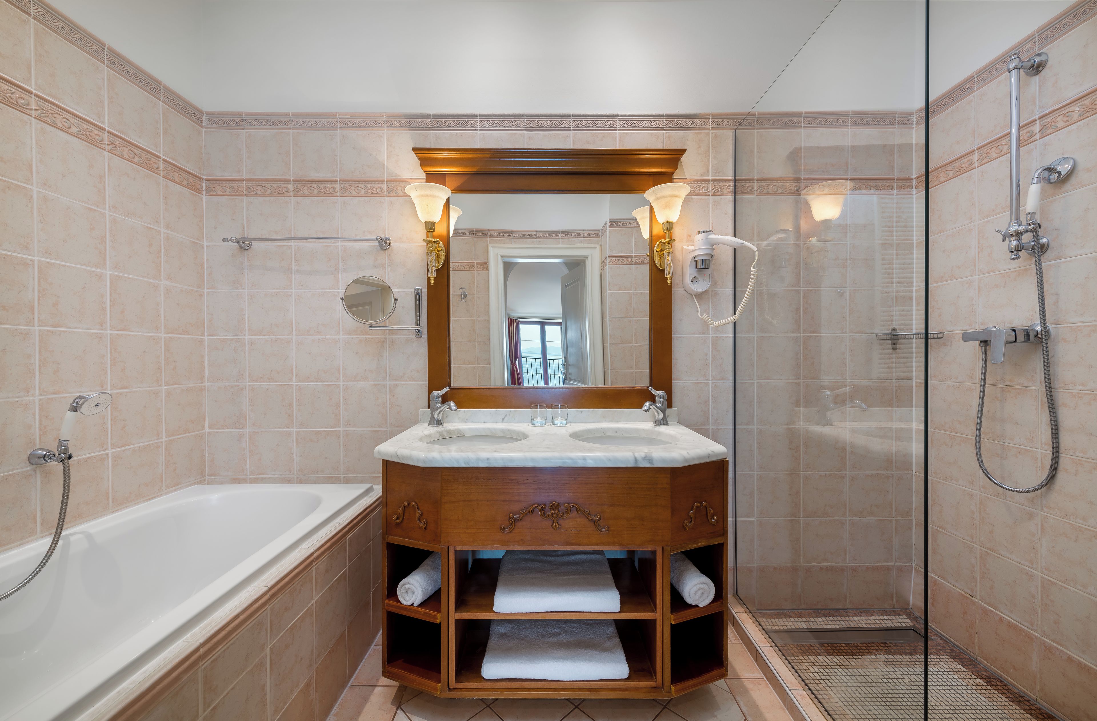 Un bagno con vasca, lavandino con mobile, cabina doccia e specchio con applique.
