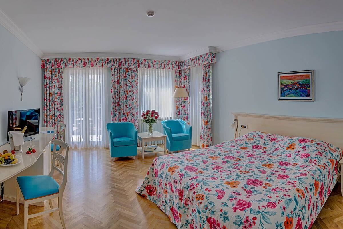 Una habitación de hotel con una cama, dos sillas, un escritorio y un televisor.