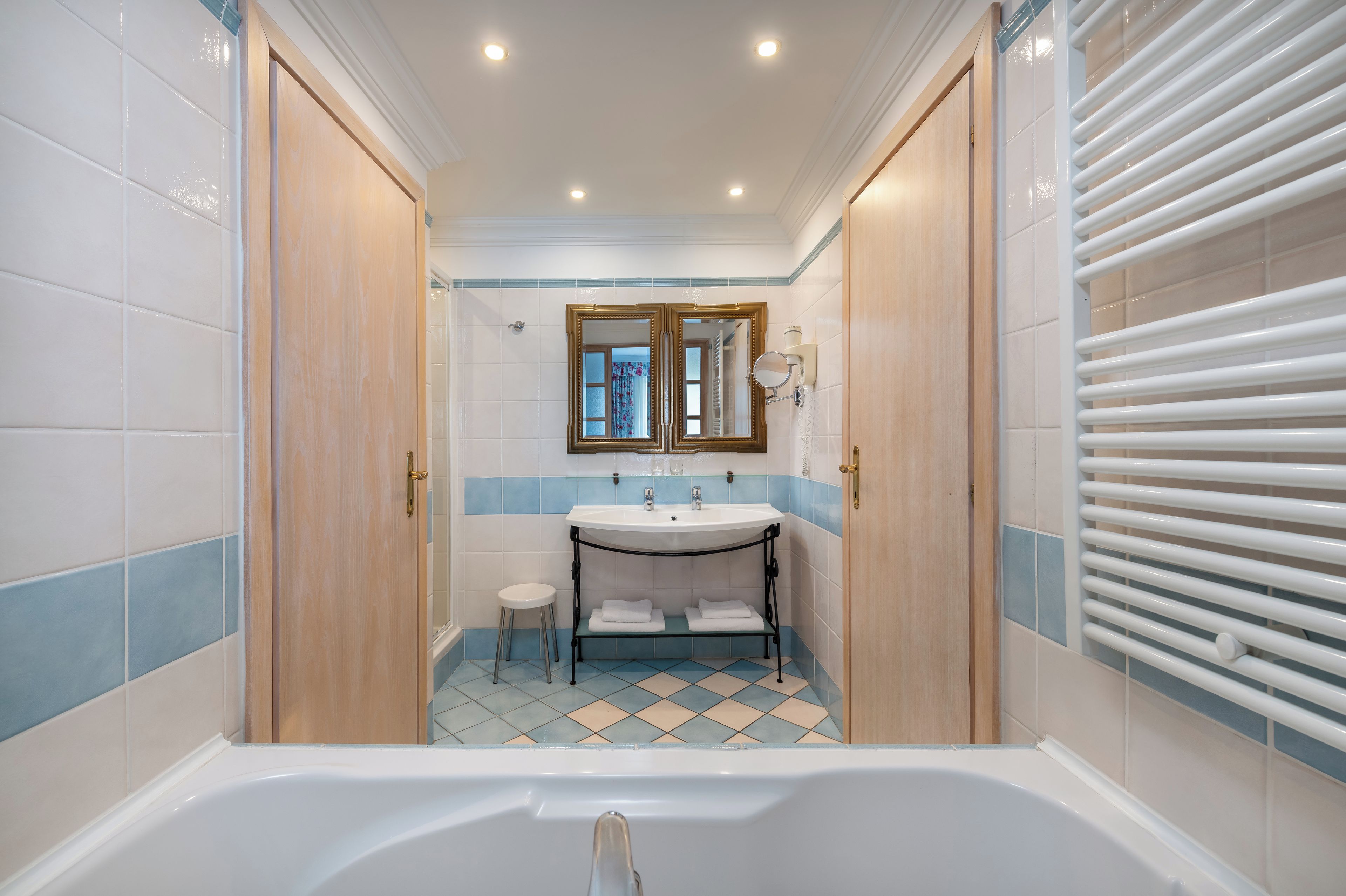A bathroom with a bathtub, a sink, a mirror, and a towel rack.