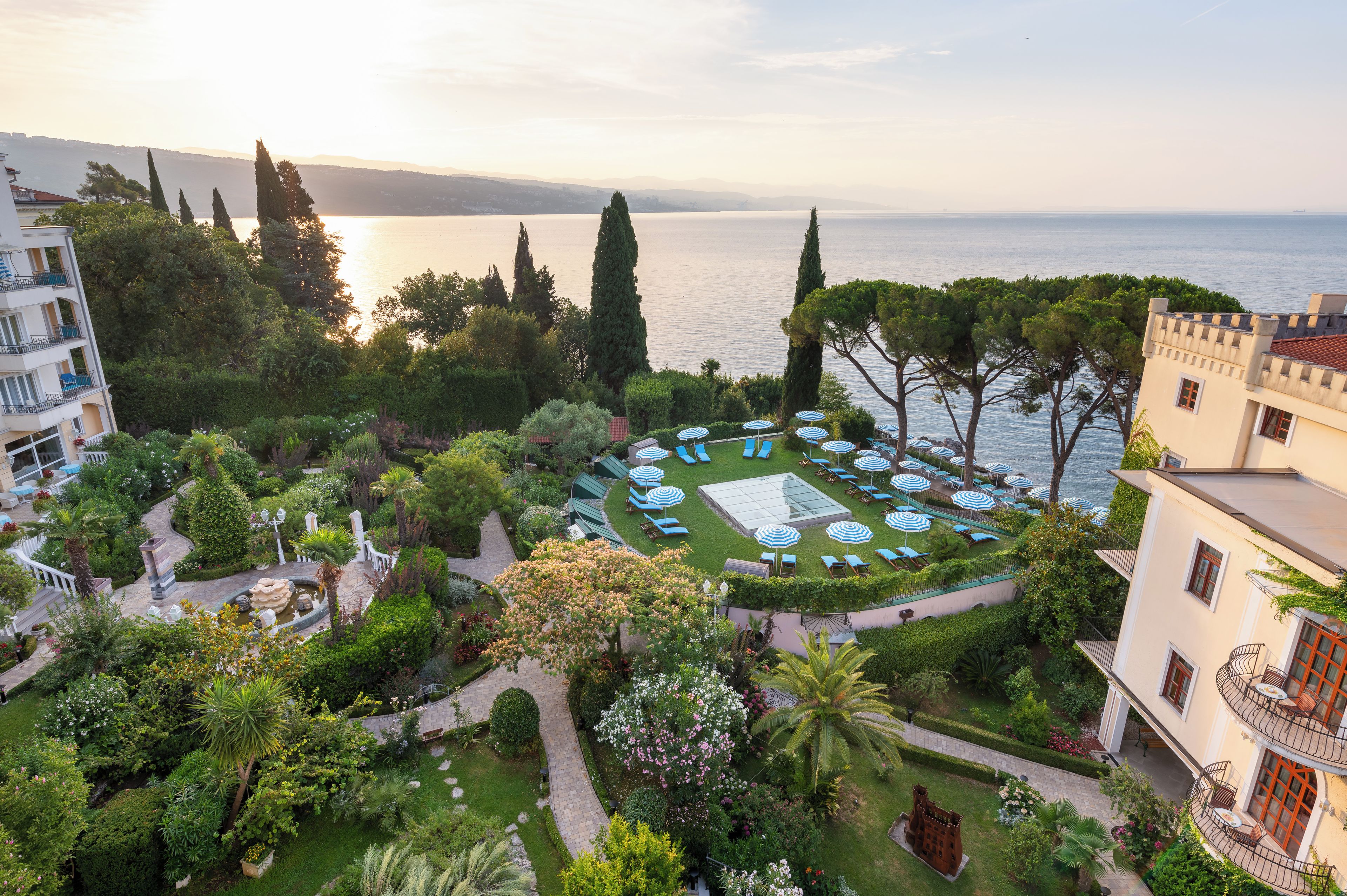 Ein angelegter Garten mit einer runden Sitzecke, Wegen und Blick auf das Meer.