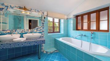 Une salle de bain avec deux lavabos, une baignoire et une fenêtre.