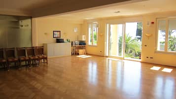Una habitación amplia con suelo de espiga, una kitchenette, una zona de comedor con sillas y ventanas grandes con vistas a zonas verdes.