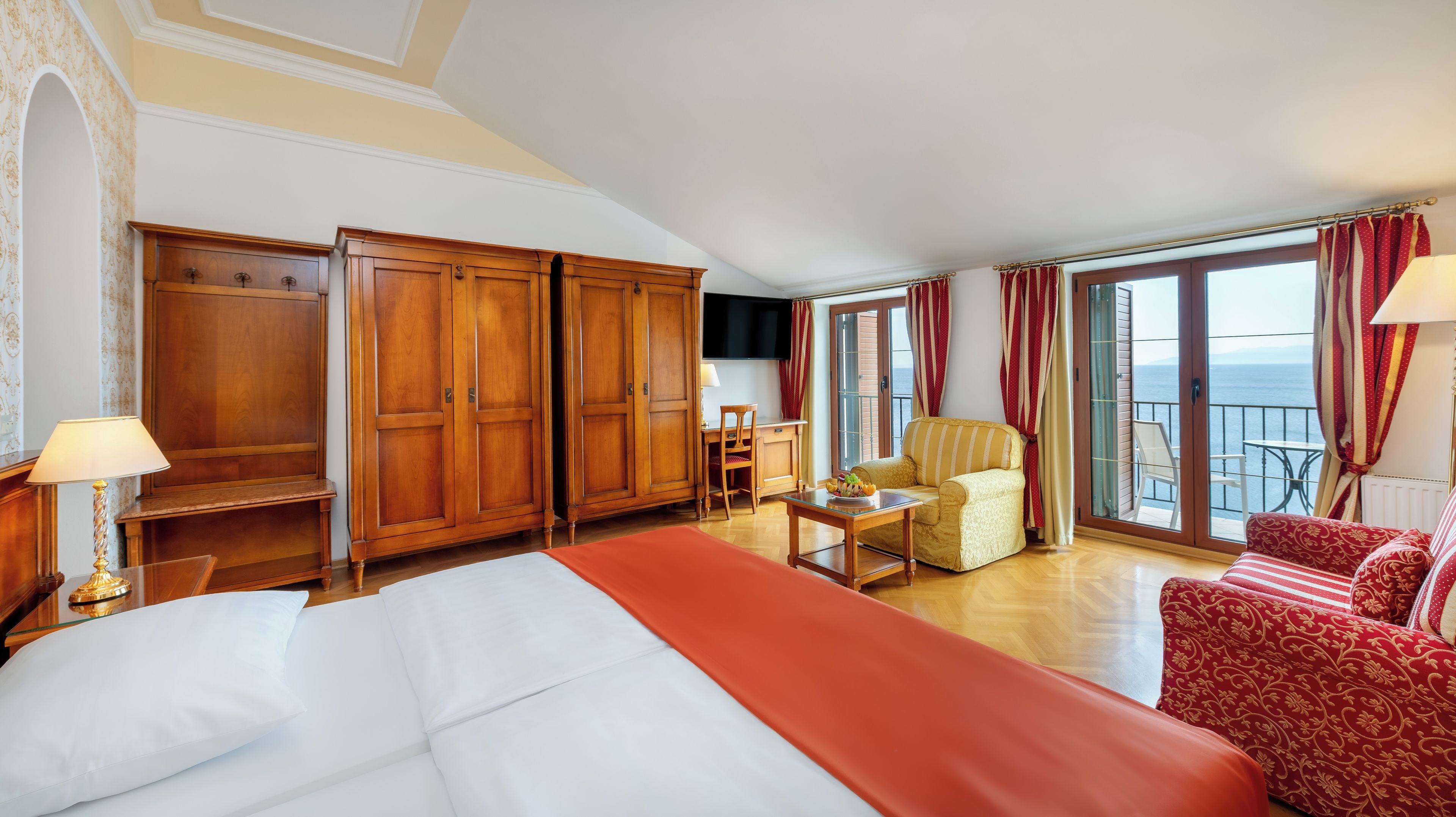 Une chambre d’hôtel avec un lit, un bureau, une chaise, un canapé et une vue sur la mer.