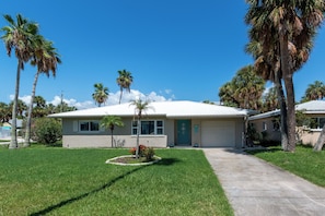 A single-story house with a front yard, palm trees, and a clear blue sky. - Paradise Corner - Monthly Beach Vacation Rental! (Clearwater Beach)