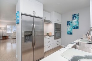 A modern kitchen with white cabinetry, stainless steel appliances, and a marble countertop. - Paradise Corner - Monthly Beach Vacation Rental! (Clearwater Beach)