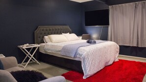A bedroom with a bed, a TV, and a red rug.