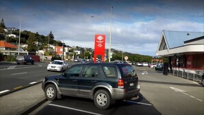 A parking lot with cars and a building with a red sign.