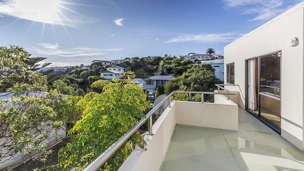 A modern building with a balcony overlooking a residential area.