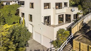 A multi-story building with large windows, a balcony, and a satellite dish.