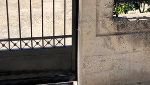 A gated entrance with a metal gate and a wall-mounted intercom. - Greece Apartments Now (Patra Achaia)