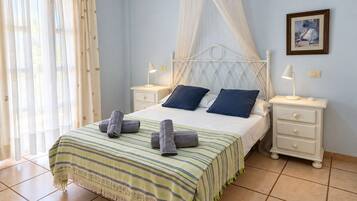 Un dormitorio con una cama, dos mesitas de noche, un cabecero y un cuadro enmarcado en la pared.