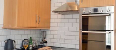 A kitchen with wooden cabinets, a stainless steel range hood, and a double oven.
