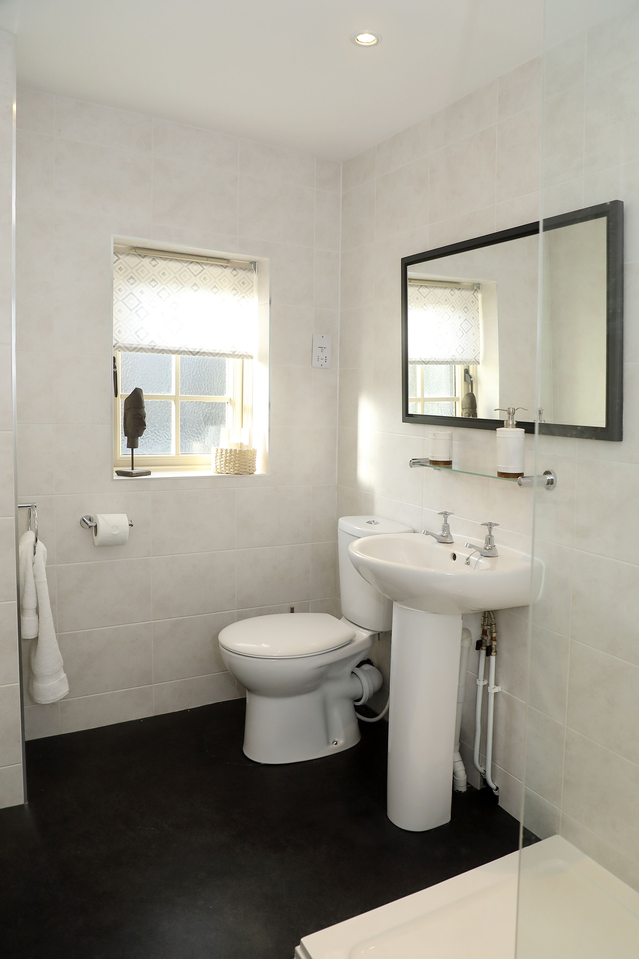 Une salle de bain avec des toilettes, un lavabo et une fenêtre.