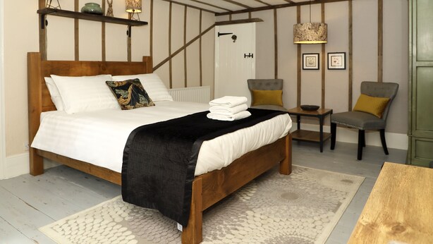 Un dormitorio con una cama de madera, una mesita de noche, una silla y un armario verde.