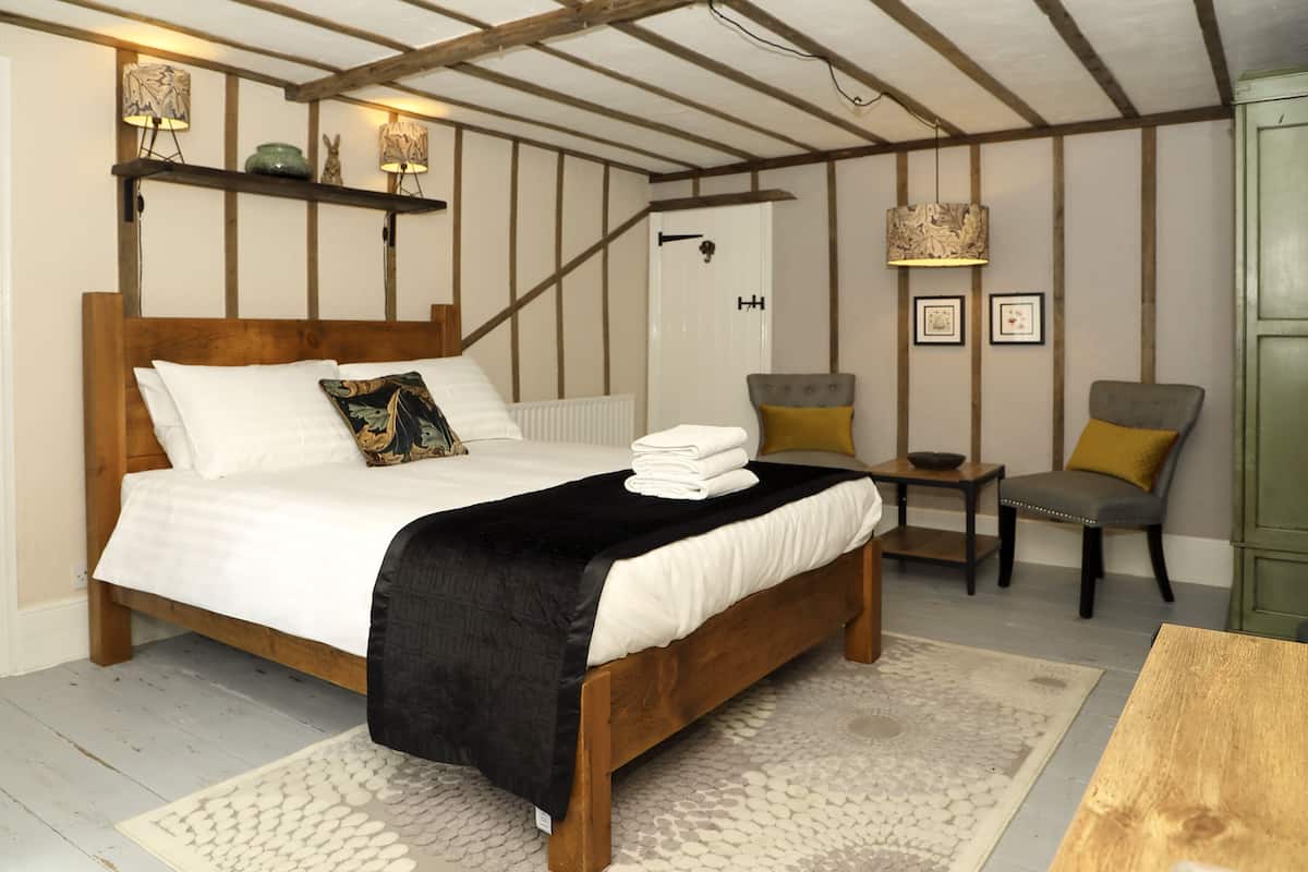 A bedroom with a wooden bed, a bedside table, a chair, and a green cabinet.
