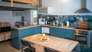 Una cocina compacta con una mesa de comedor de madera, microondas y un lavabo.