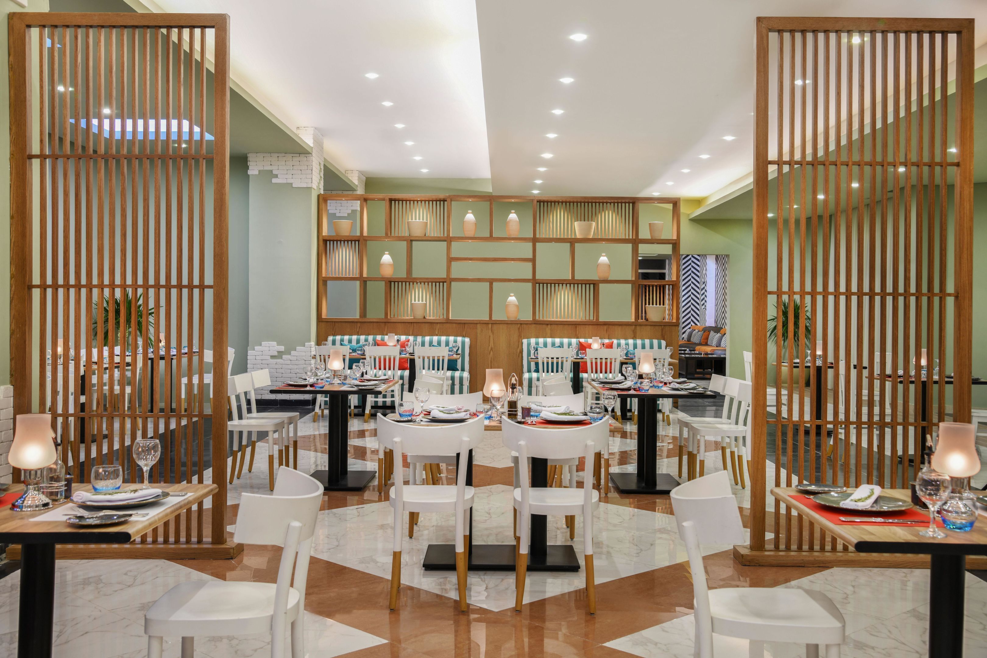 A restaurant with multiple tables, chairs, and a decorative wooden partition.