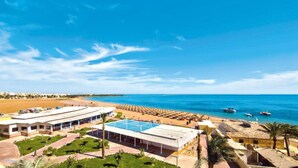 Un resort con una piscina grande, zona de playa y vista al océano.
