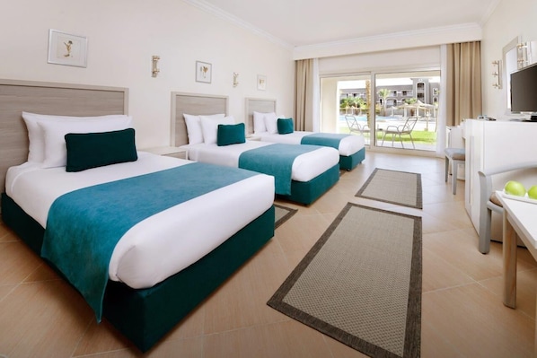 Habitación de hotel con dos camas, televisión, escritorio y vistas al área exterior.