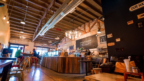 A cozy cafe with a rustic interior, featuring exposed brick walls, wooden tables, and a central bar area. - Modern Waterfront Lakehouse, with a private beach and a spacious boat dock. (Lake Placid)