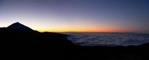 A mountain silhouette against a sunset sky.