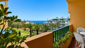 Un balcón con vista al mar, una piscina y un edificio de varios pisos.