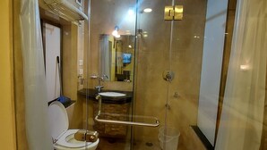 Un baño con mampara de vidrio, inodoro, lavabo y zona de ducha.