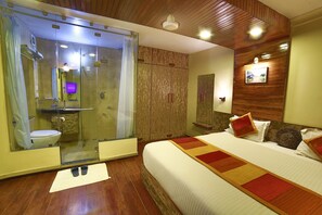 A bedroom with a large bed, a glass-enclosed shower, and a wooden ceiling. - Shaleen Elegance Homestay (Abu Road)