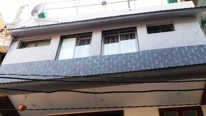 Un edificio de dos pisos con balcón, antena parabólica y una ventana con cortina.