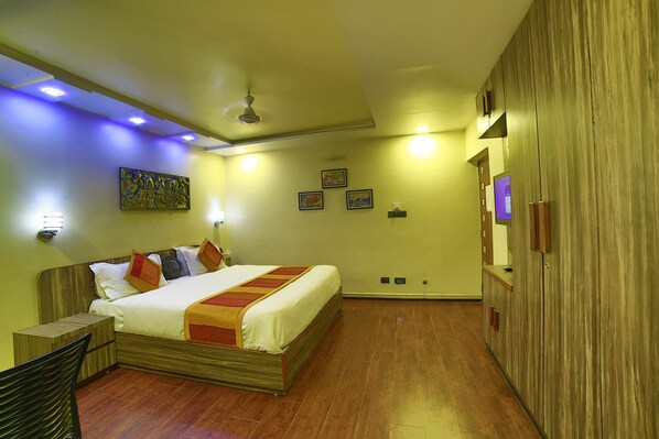 A hotel room with a wooden bed, a nightstand, a chair, and a wardrobe. - Shaleen Elegance Homestay (Abu Road)