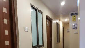 Un pasillo con suelo de madera, una puerta con número y una ventana.